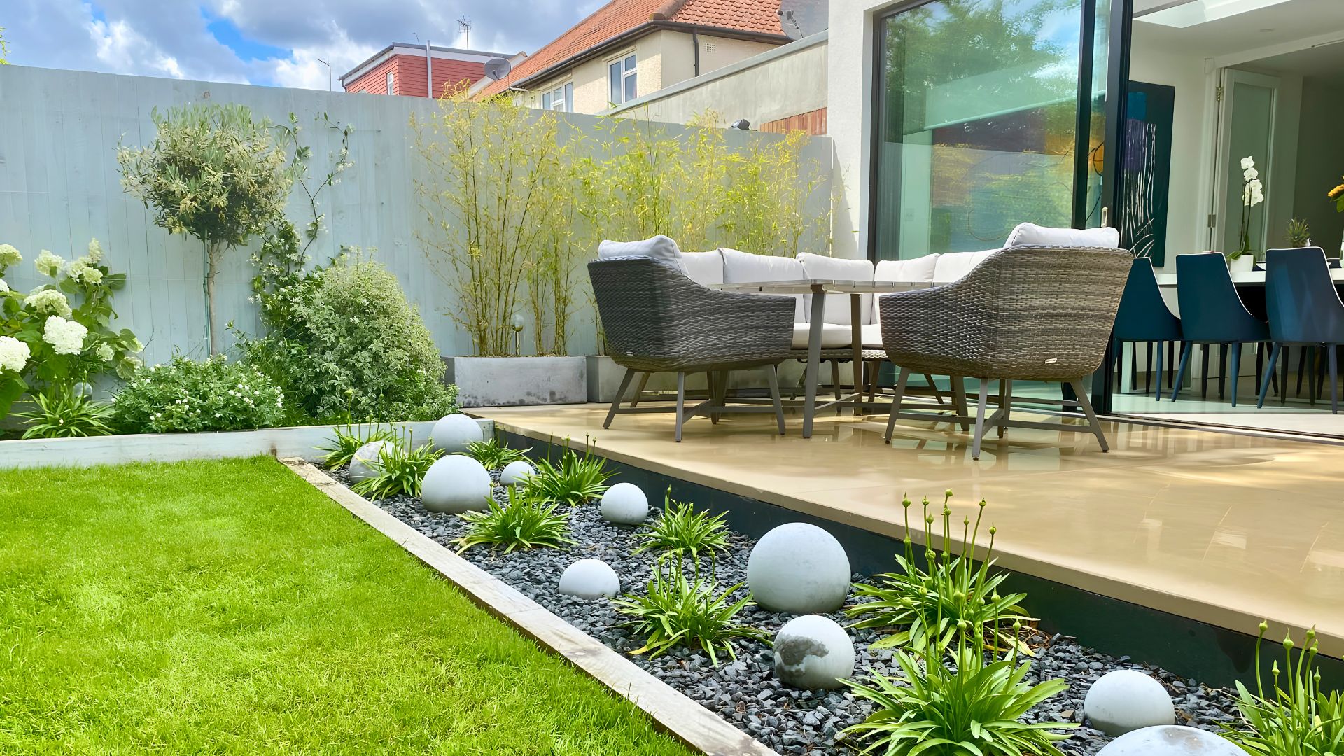 Grey gravel border with sculptural stone spheres, modern garden landscaping detail