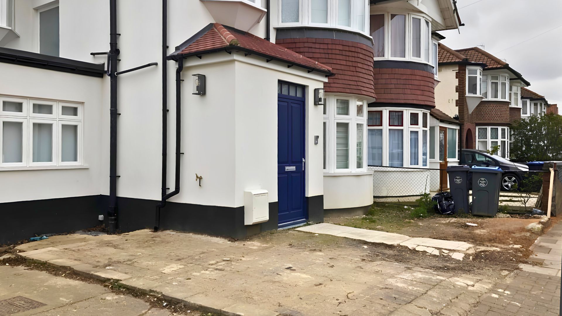 The Wembley front garden before transformation — a tired, cracked hard-standing driveway with weeds and wheelie bins